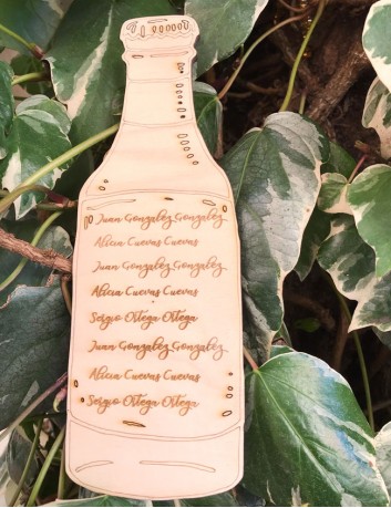 Botellas en madera natural con el nombre de los invitados grabados sobre la madera para distribuir mesas boda
